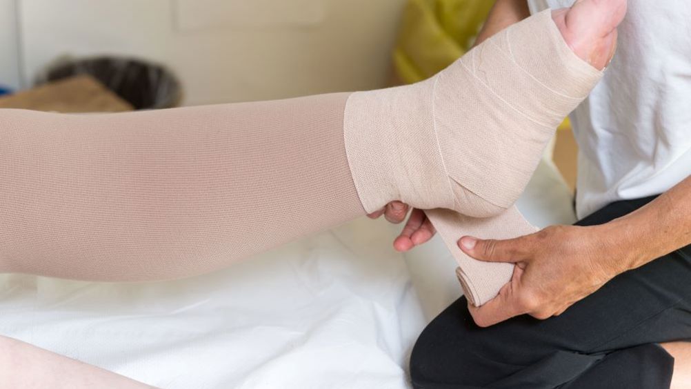 a person is putting a bandage on a patient 's leg .