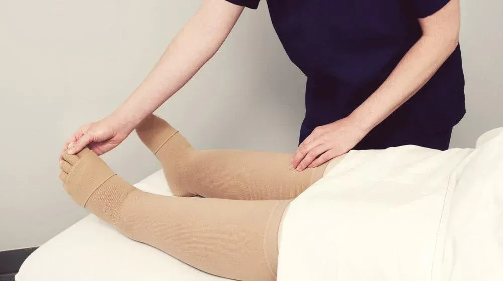 a person is laying on a bed with a bandage on their leg .