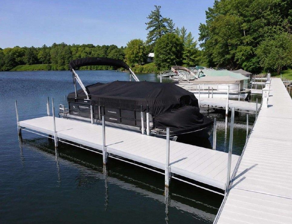 Modern dark-gray cabin with large windows, set on a green lawn near trees and a lake