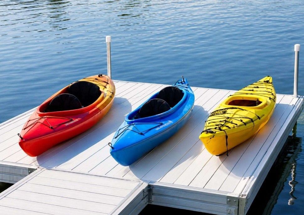 Two red kayaks on a wooden dock by a calm lake with trees reflected in the water