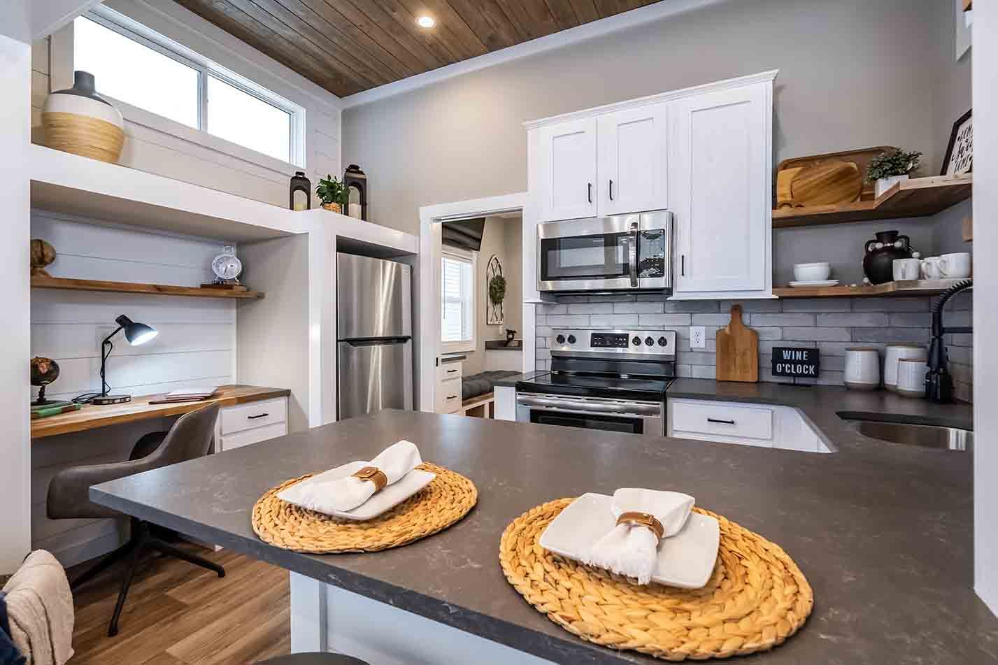 Modern kitchen with gray island, white cabinets, open shelves, and two woven placemats with bread on the counter