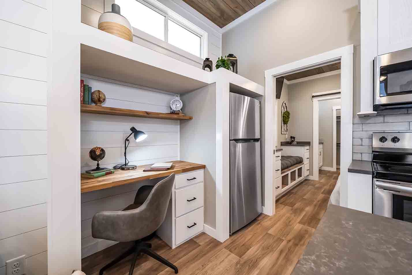 Modern kitchen with a built-in desk nook, stainless fridge, and wood flooring
