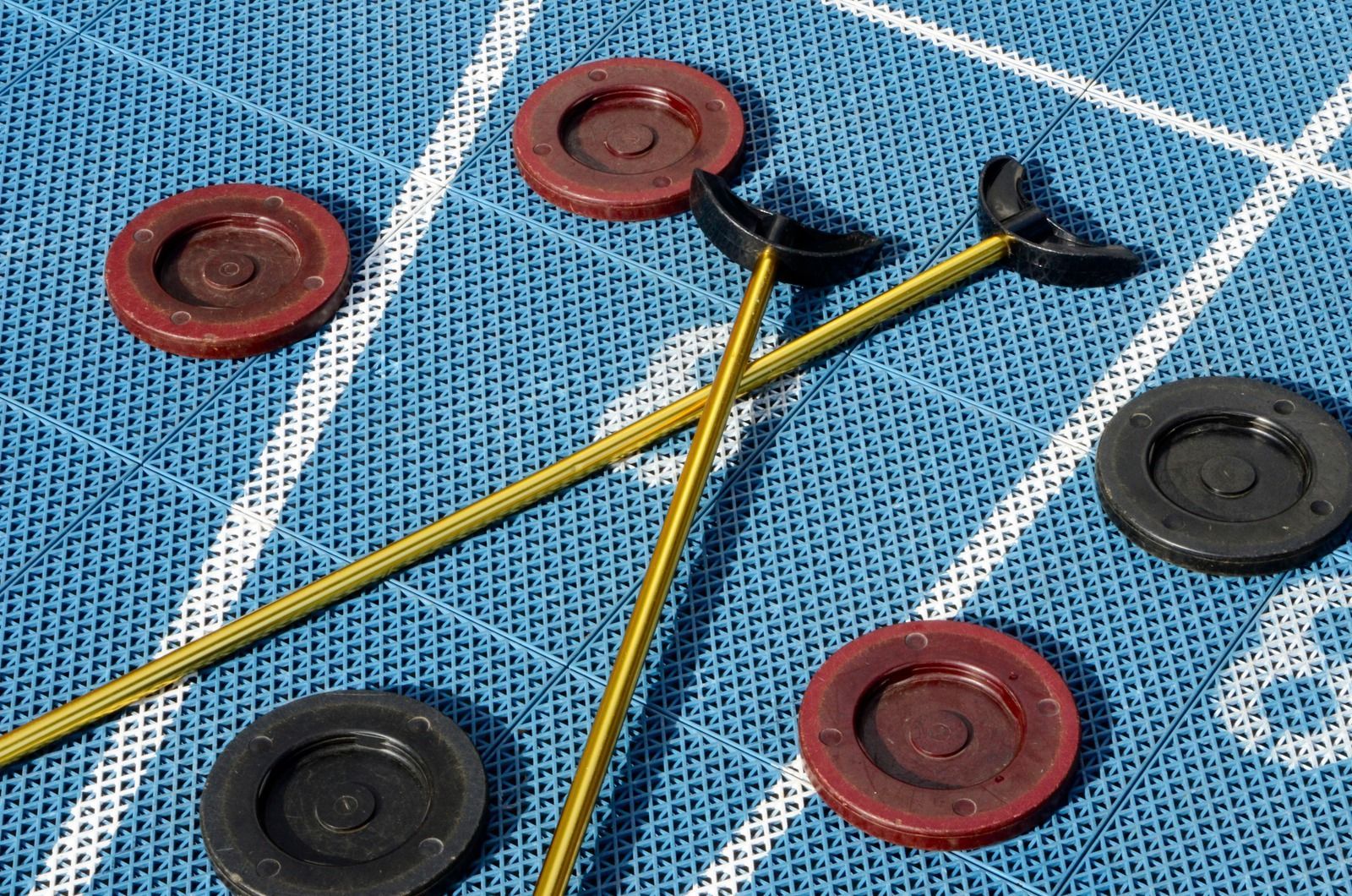 Shuffleboard pucks and cues on a blue scoring board with white grid lines
