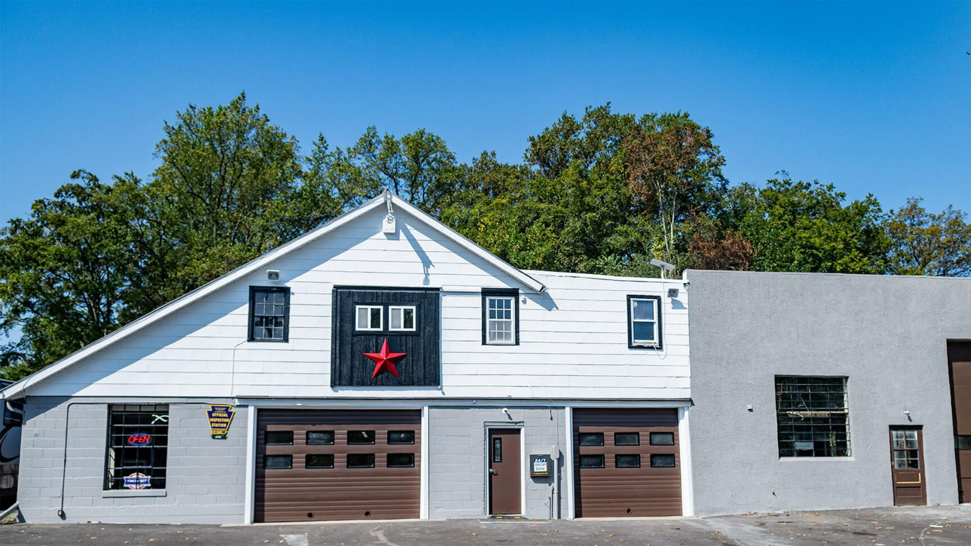Parking lot beside a brick building with parked blue, silver, and red vehicles under a sign. | Dave's Auto and Truck Service