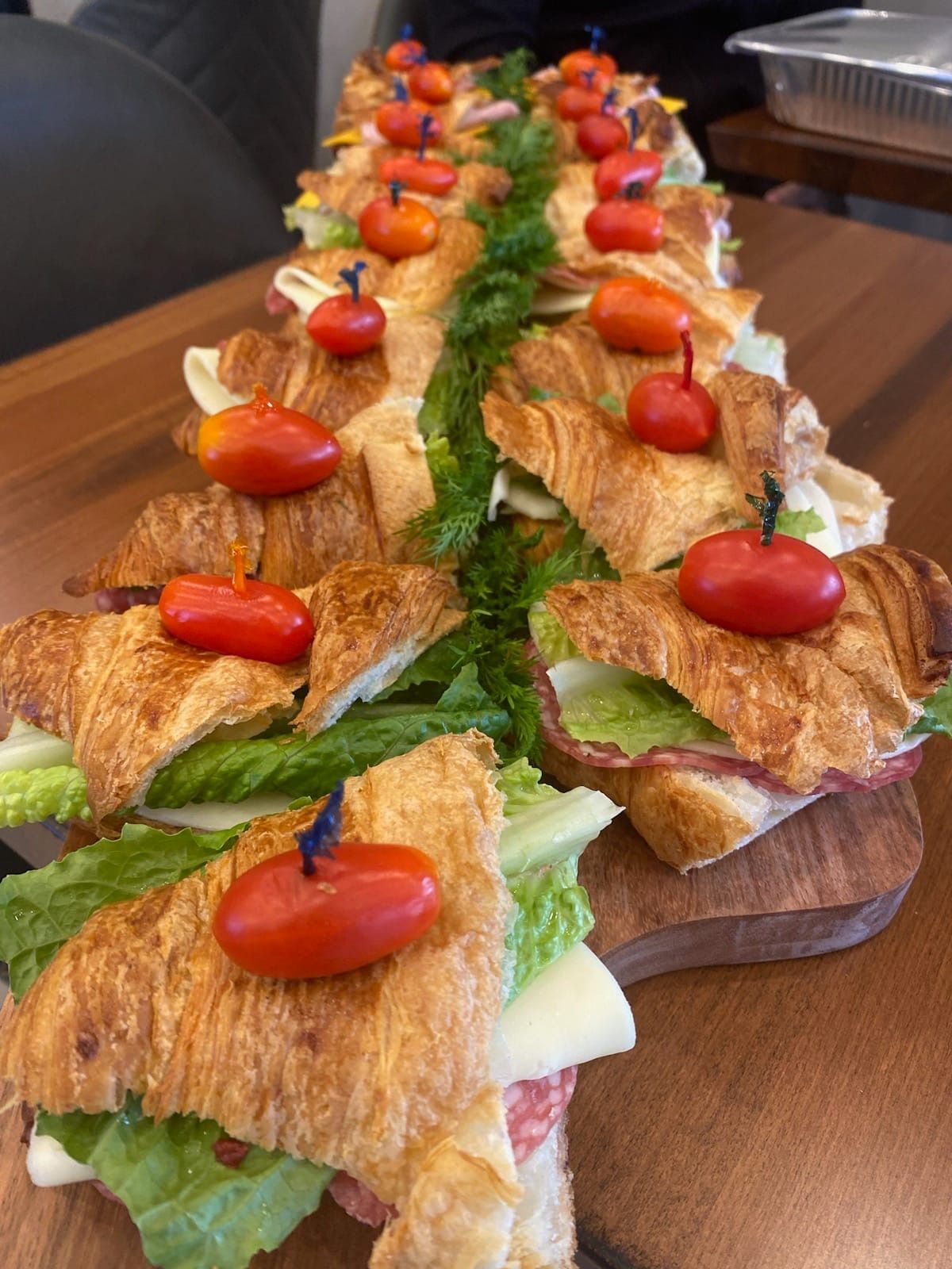 a row of sandwiches on croissants with tomatoes on top