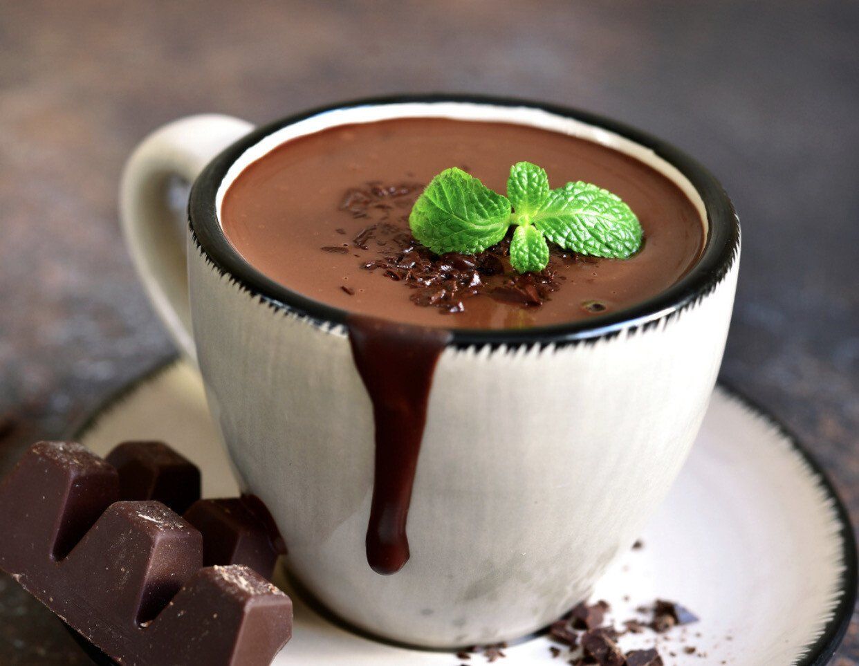 a cup of hot chocolate with mint leaves on top