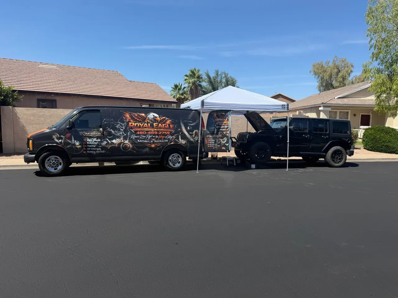 Two black vans parked side by side on a street, connected by a white canopy
