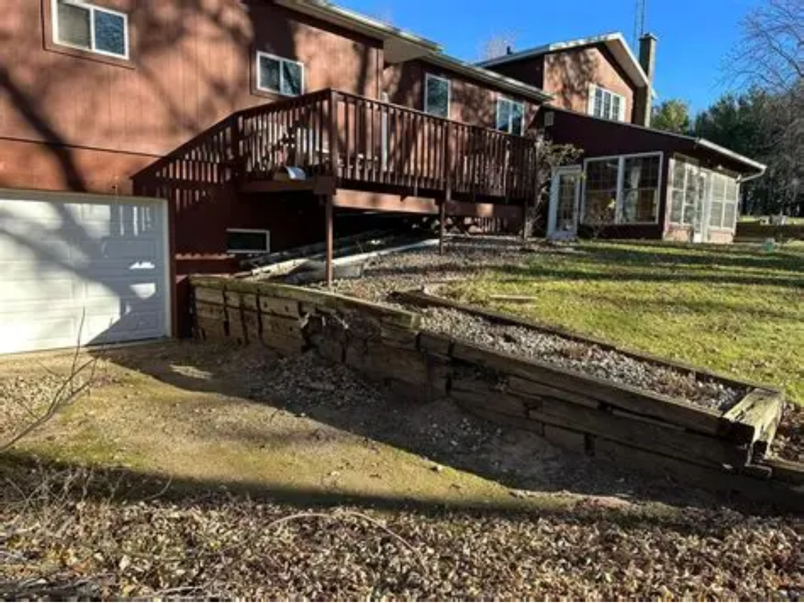 House exterior with wooden deck, ramp, and garage on a sunny day
