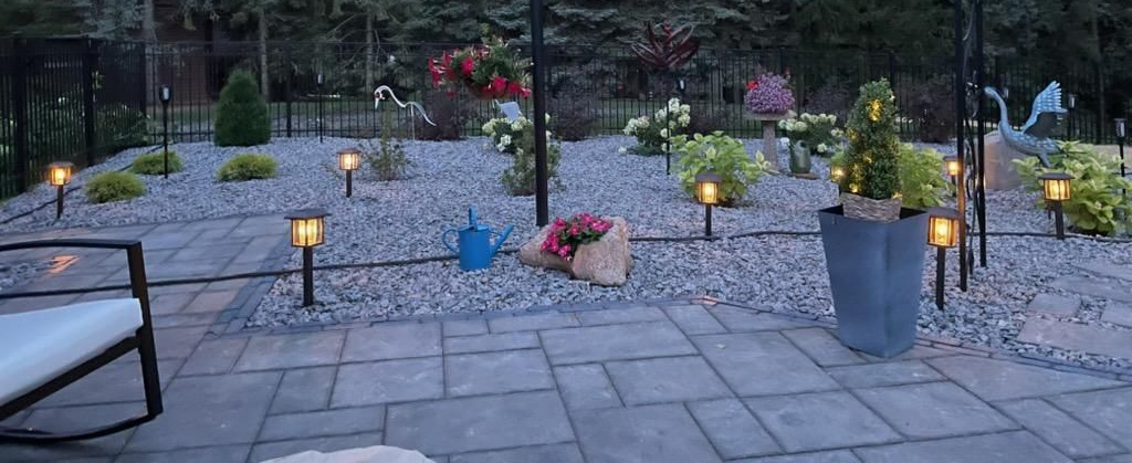 Curving lit garden path at night with plants, rocks, and warm landscape lights