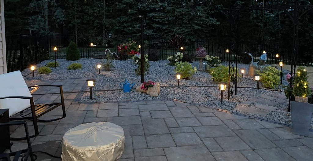 Warmly lit brick house at night with glowing windows, trees, and a front walkway lining the entrance
