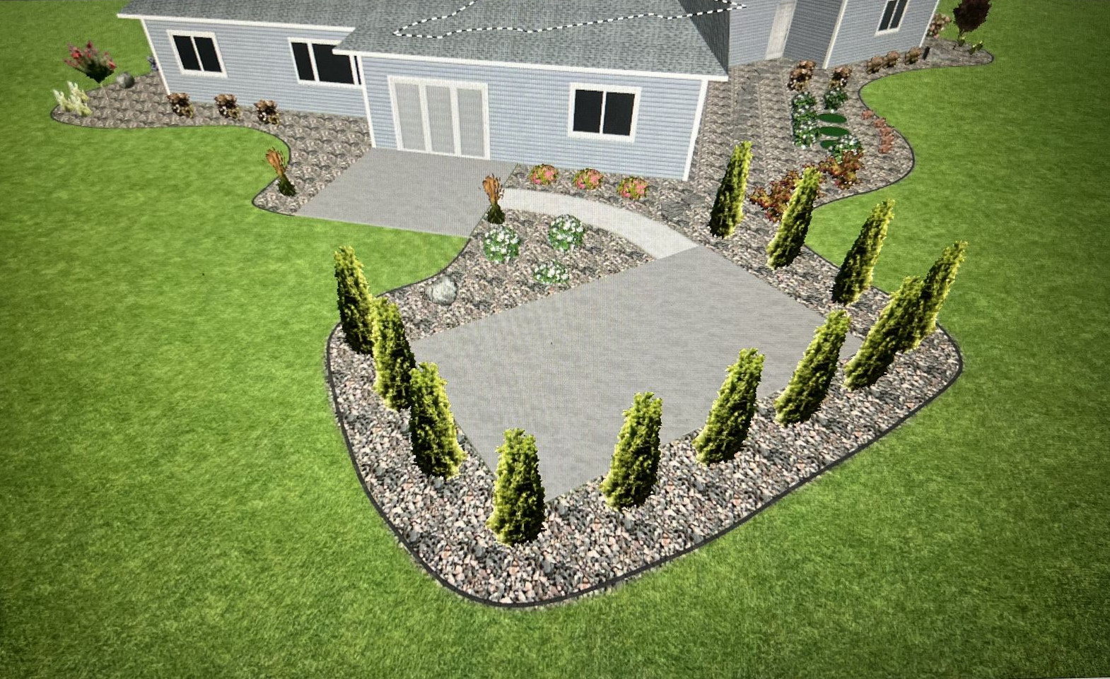 Front yard with curved stone retaining wall, paved walkway, and landscaped shrubs beside a gray house