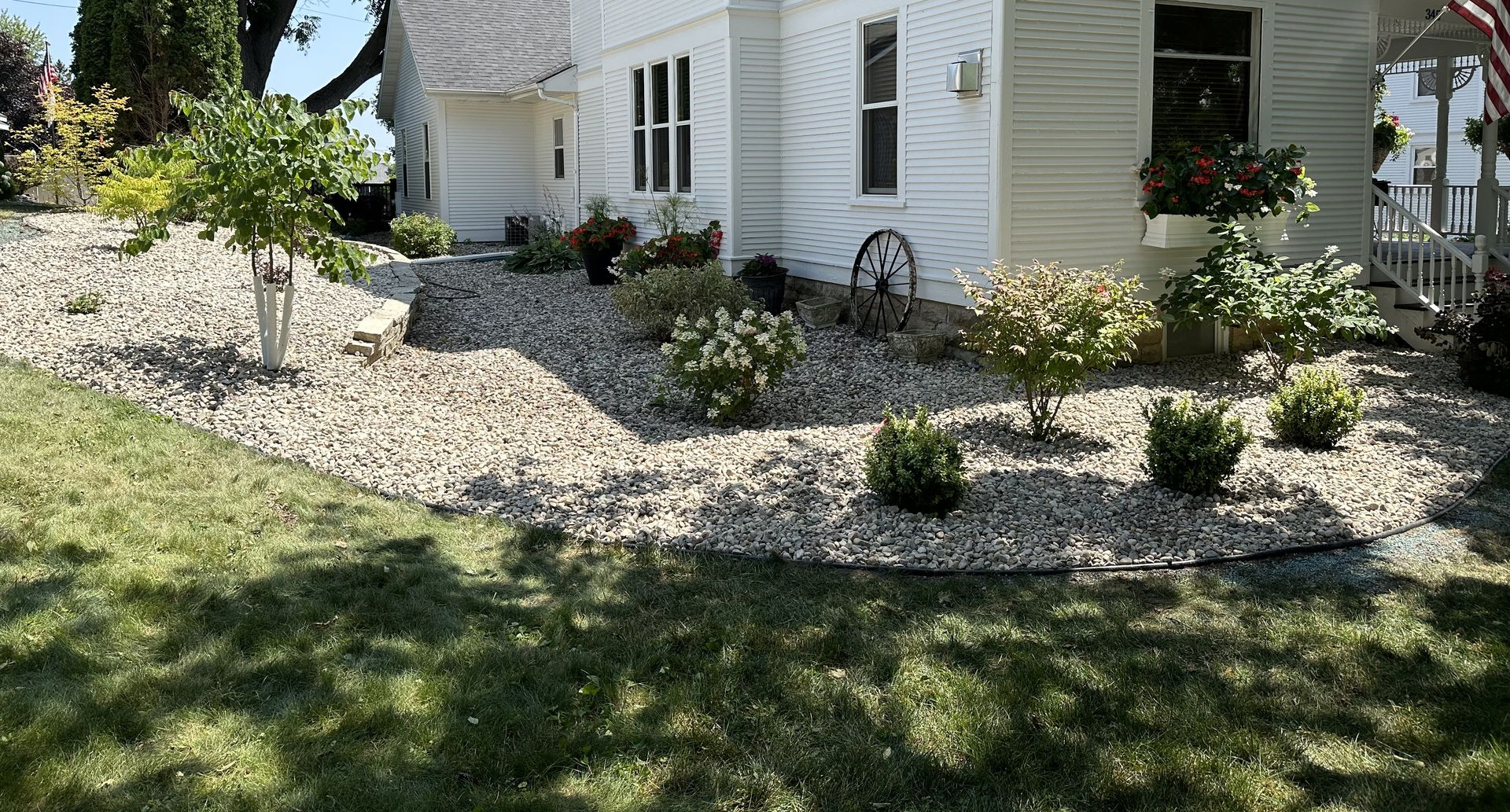 Curved garden bed with colorful shrubs and flowers beside a green lawn and path