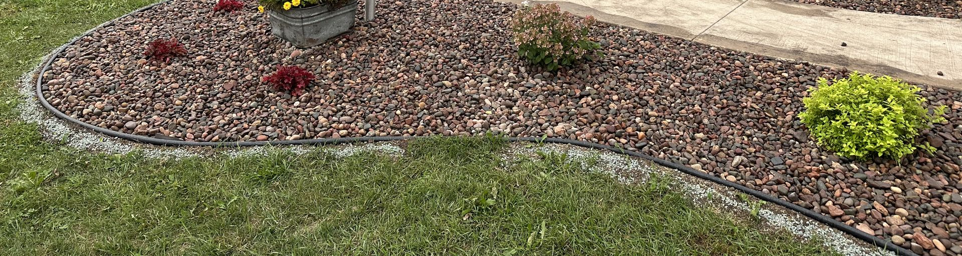 Curved stone garden border beside colorful flowers and green lawn