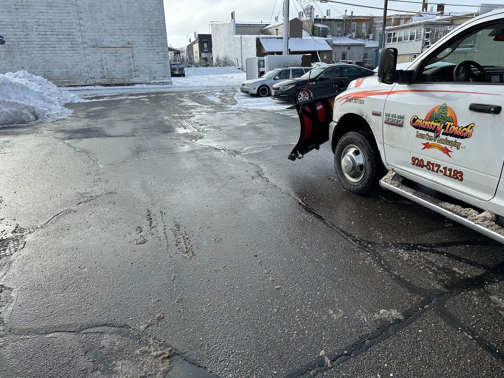 Snow-covered driveway leading to a street, with tall snowbanks on both sides.