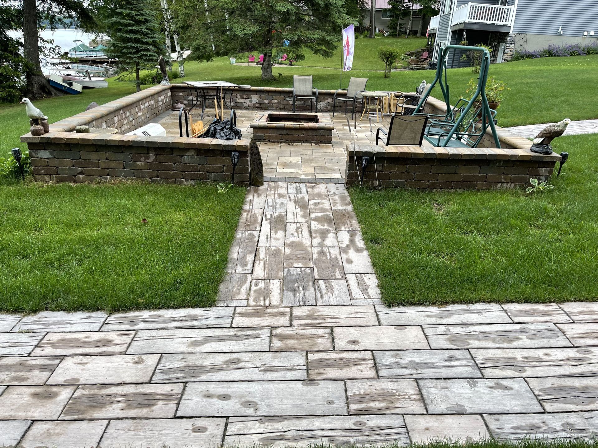Stone walkway leading to a small raised garden pond in a grassy yard
