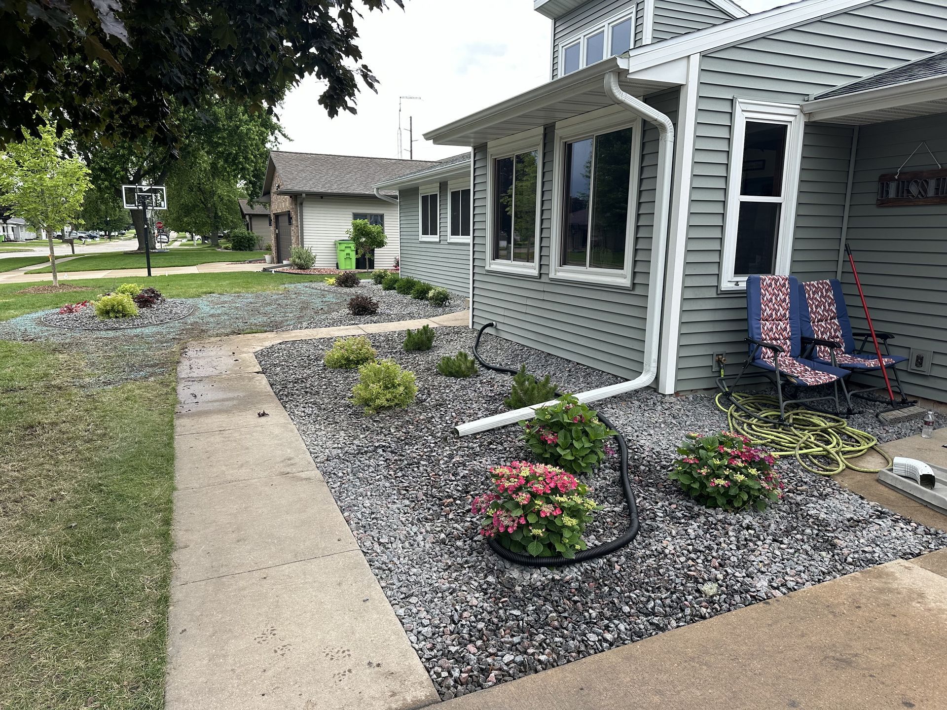 Lush garden bed with pink and yellow flowers, green foliage, and a mulched path.