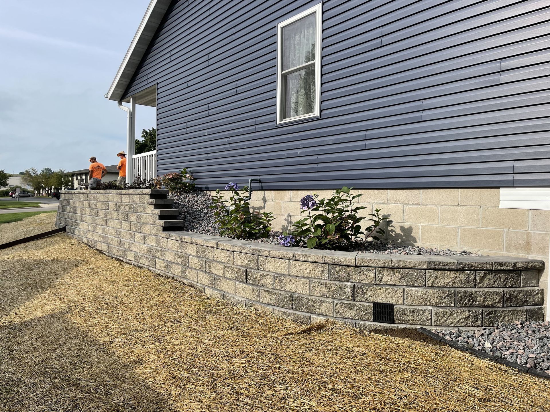 Backyard patio with stone retaining wall and lawn by Country Touch Landscaping near Fond du Lac, WI