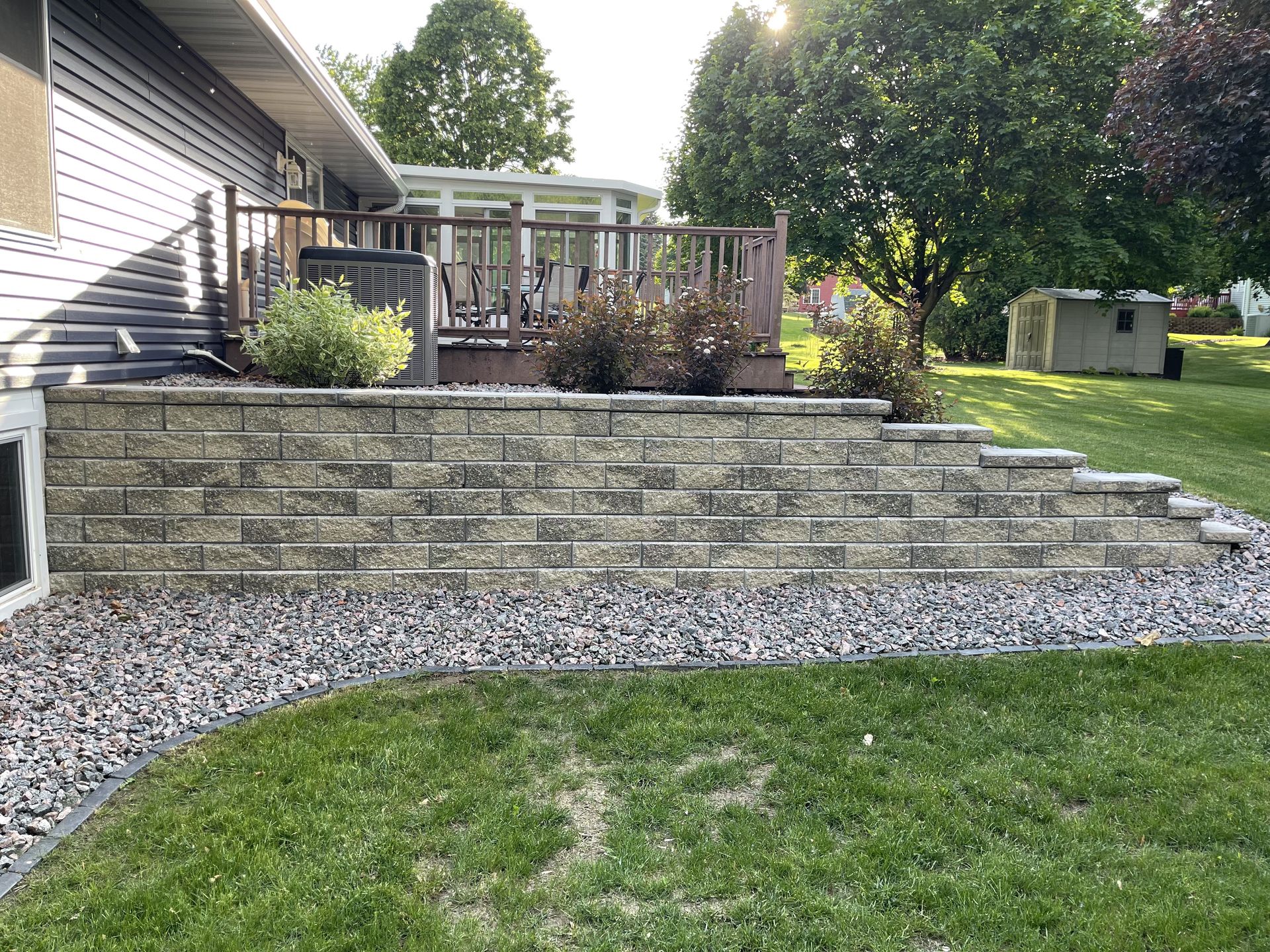 Backyard patio with stone retaining wall and lawn by Country Touch Landscaping near Fond du Lac, WI