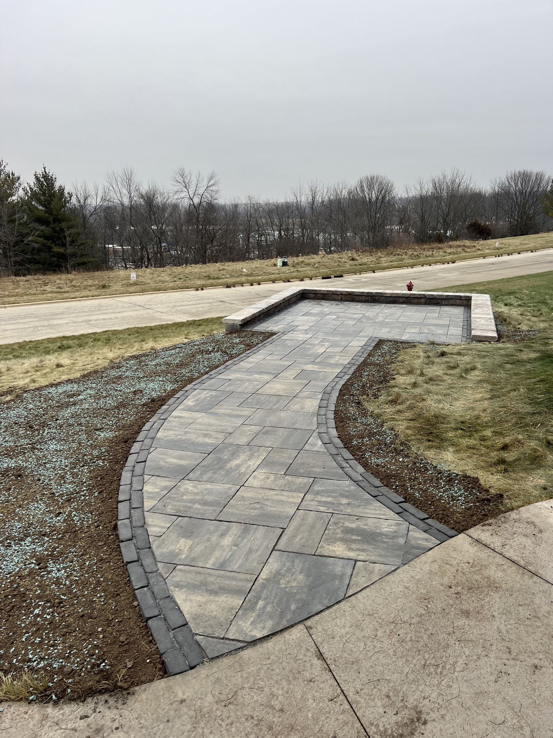 Curved stone walkway with raised edges in a grassy outdoor park under an overcast sky