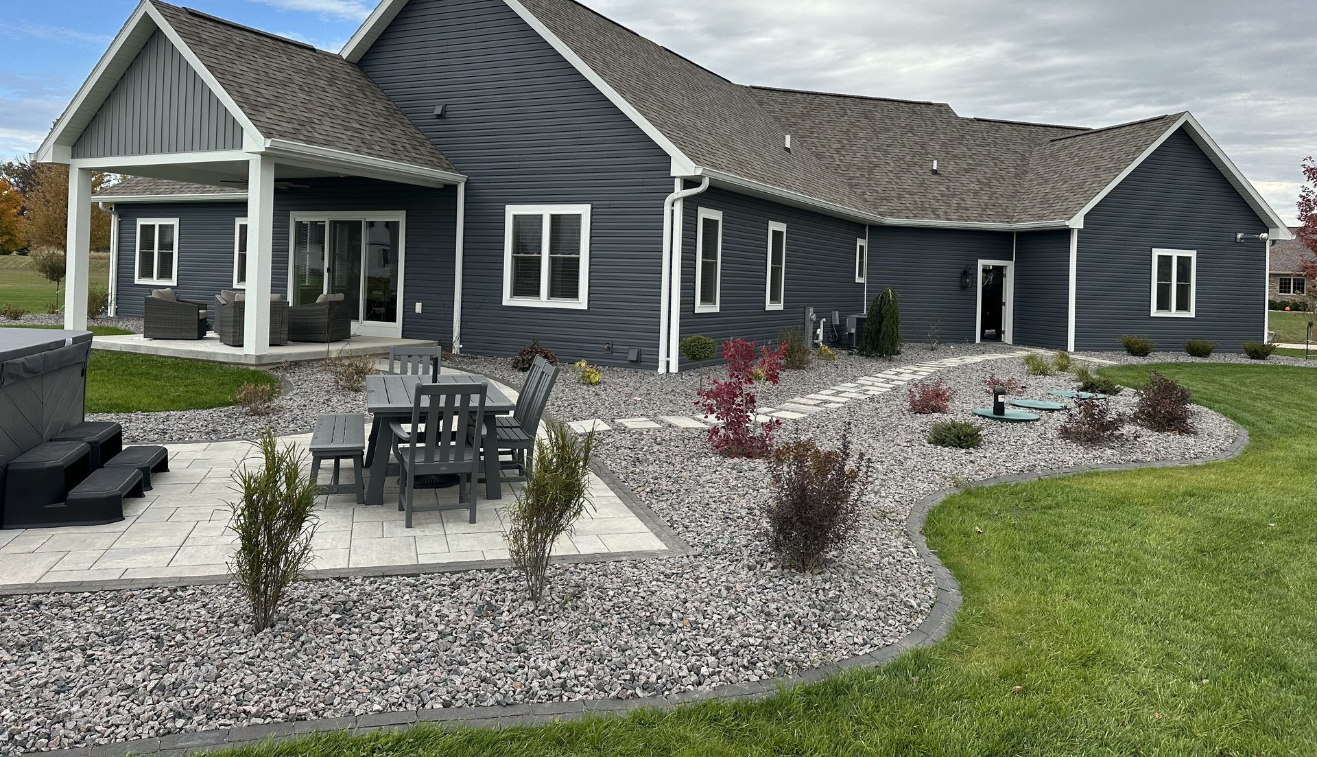 Charming house with arched porch, colorful flower beds, and a manicured green lawn