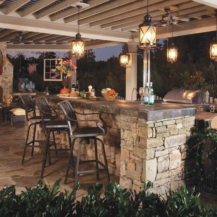 Covered outdoor patio with stone bar, lantern lights, and tall chairs at sunset