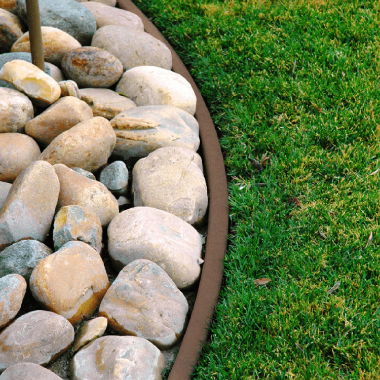Decorative river rocks bordered by metal edging beside a green lawn