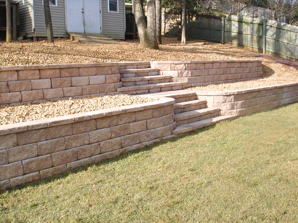 Backyard retaining wall with stone steps and a curved raised garden bed