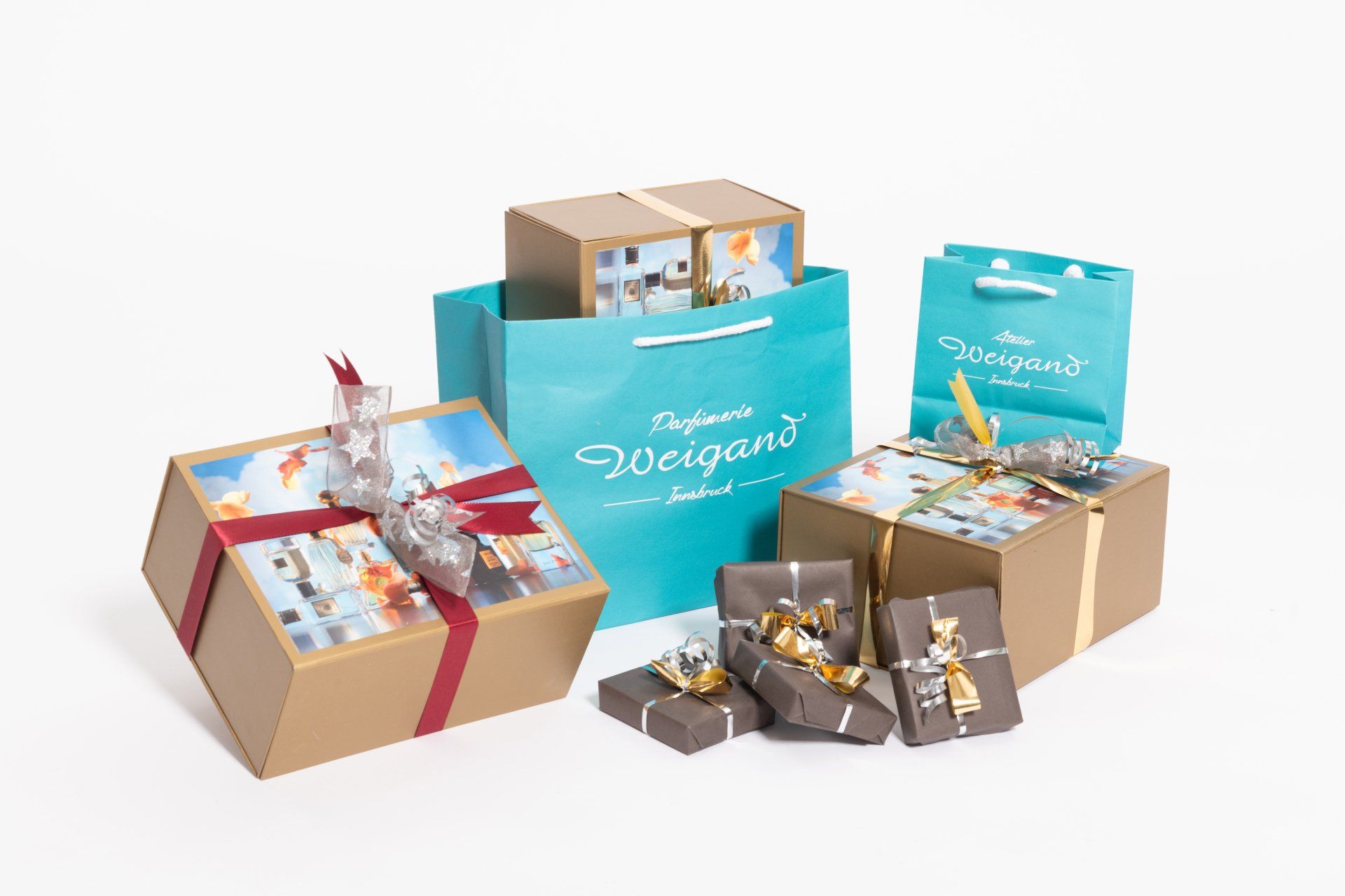 Verschiedene Geschenkboxen und -tüten in Türkis, Beige und Rot mit Schleife auf weißem Hintergrund