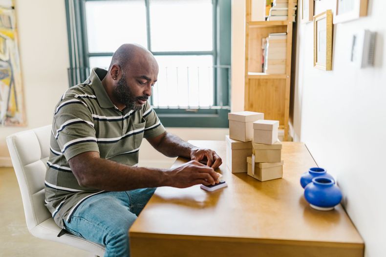 Established Black small-business owner reviewing plans at a worktable