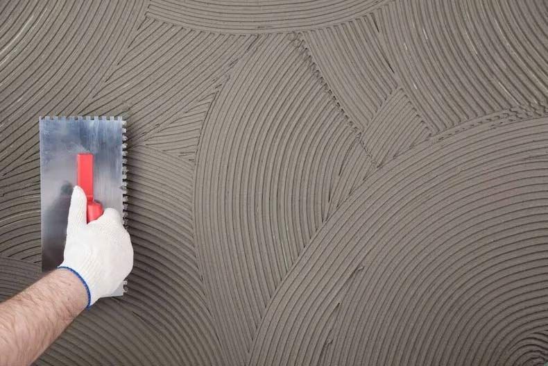 A Person Is Applying Concrete To A Wall With A Trowel — Ingham Concrete–Icon in Ingham, QLD