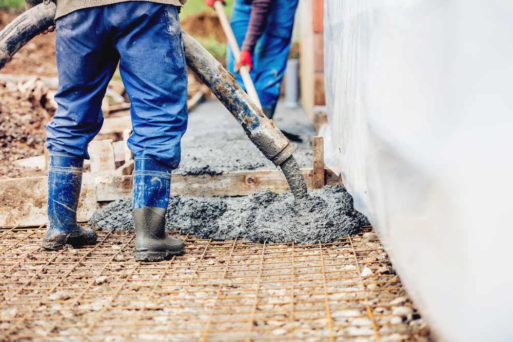 Worker Laying Concrete With An Automatic Pump — Ingham Concrete–Icon in Cardwell, QLD