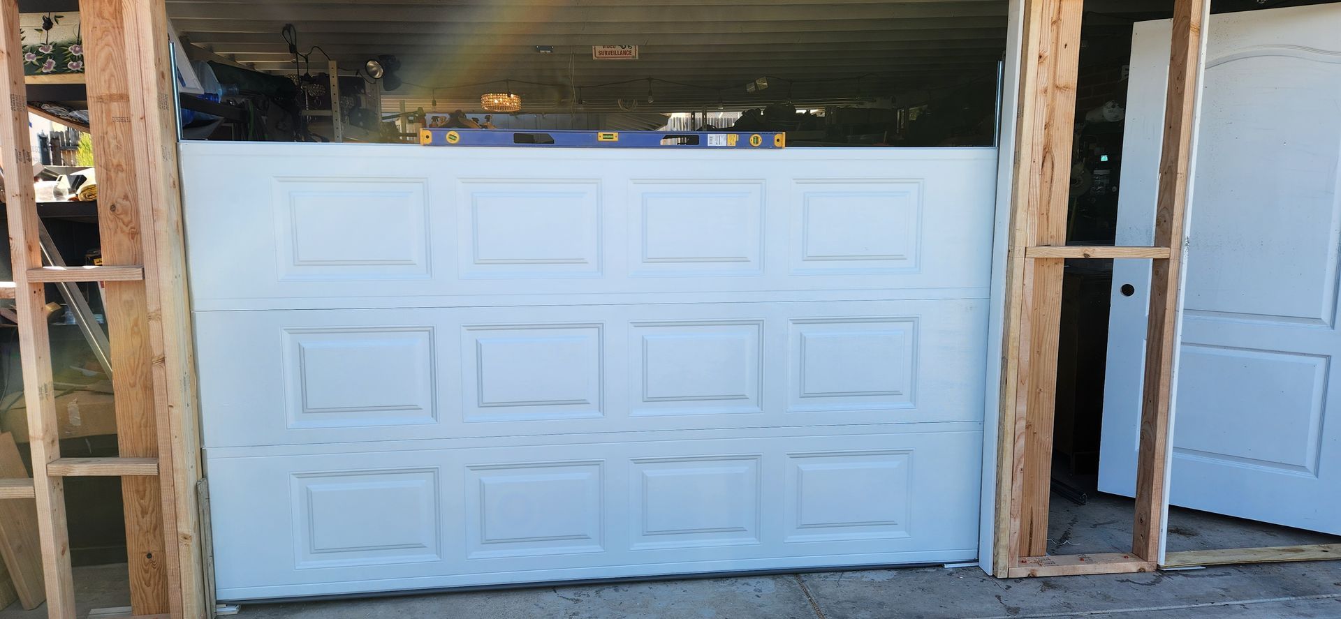A white garage door is being installed in a garage.