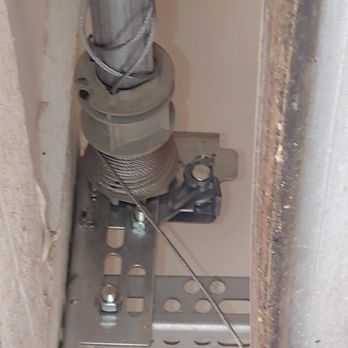 A close up of a garage door spring with a cable attached to it.