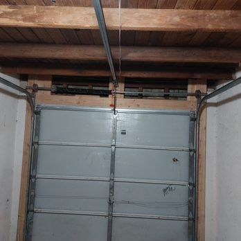 A garage door is open in a room with a wooden ceiling.