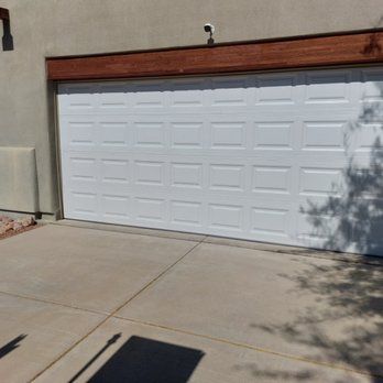 A white garage door is sitting in front of a house.