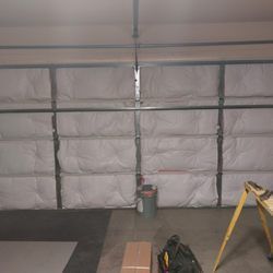A garage door with insulation on it and a ladder.