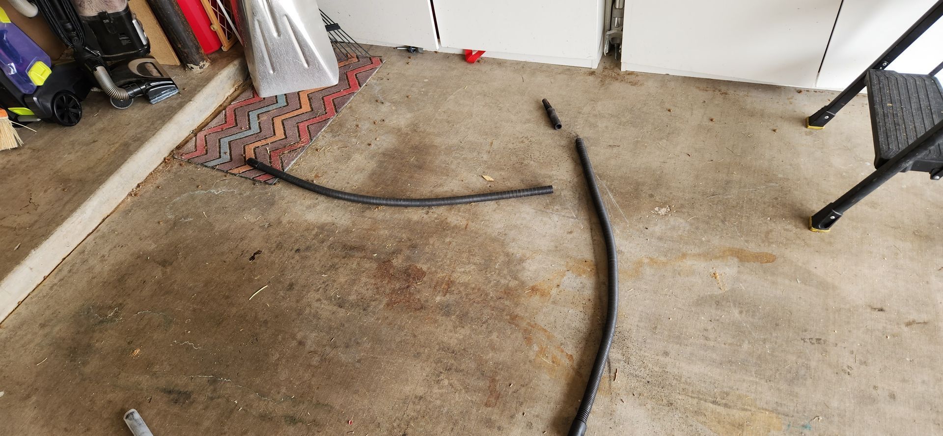 A broken piece of wire is laying on the floor in a garage.