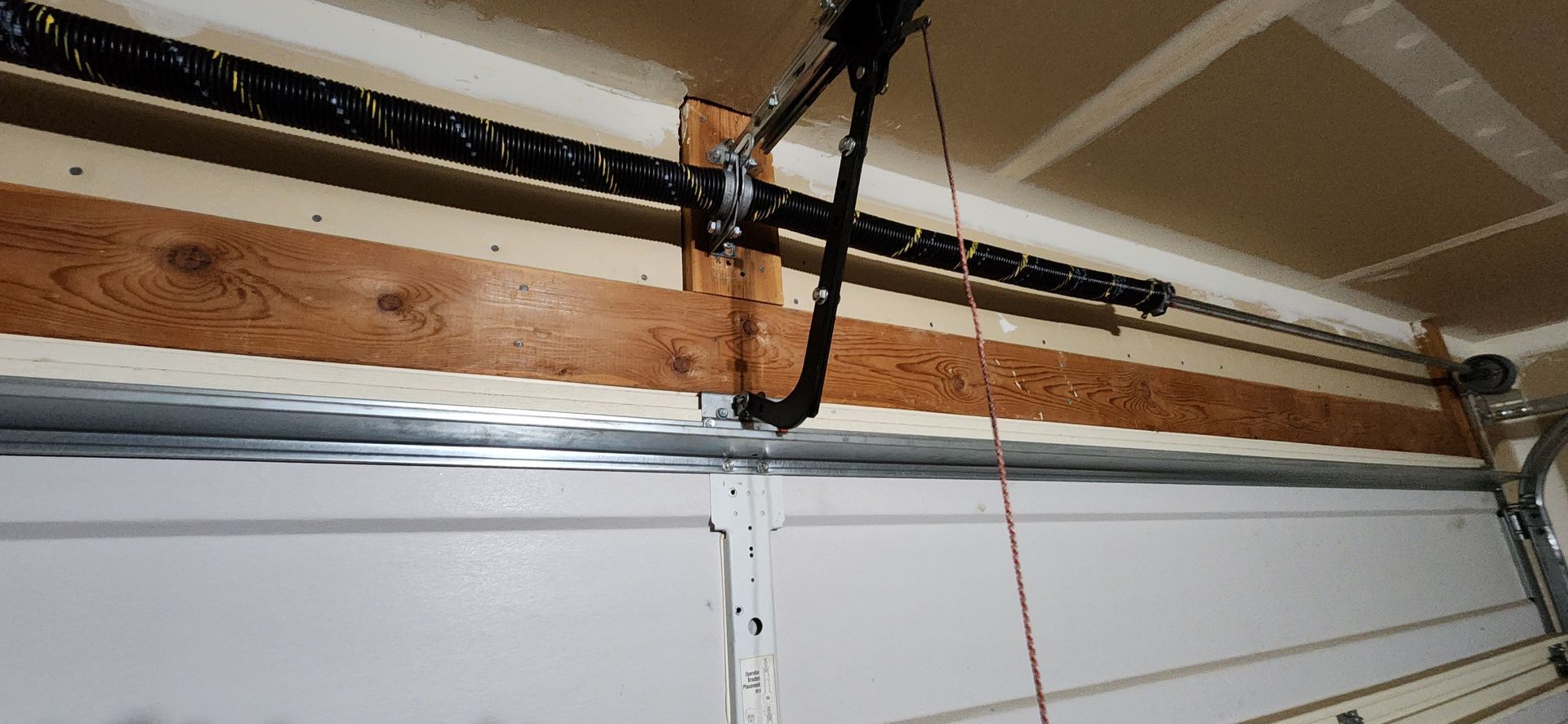 A garage door opener is hanging from the ceiling of a garage.