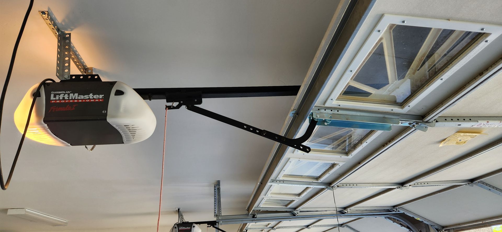 A garage door opener is hanging from the ceiling of a garage.