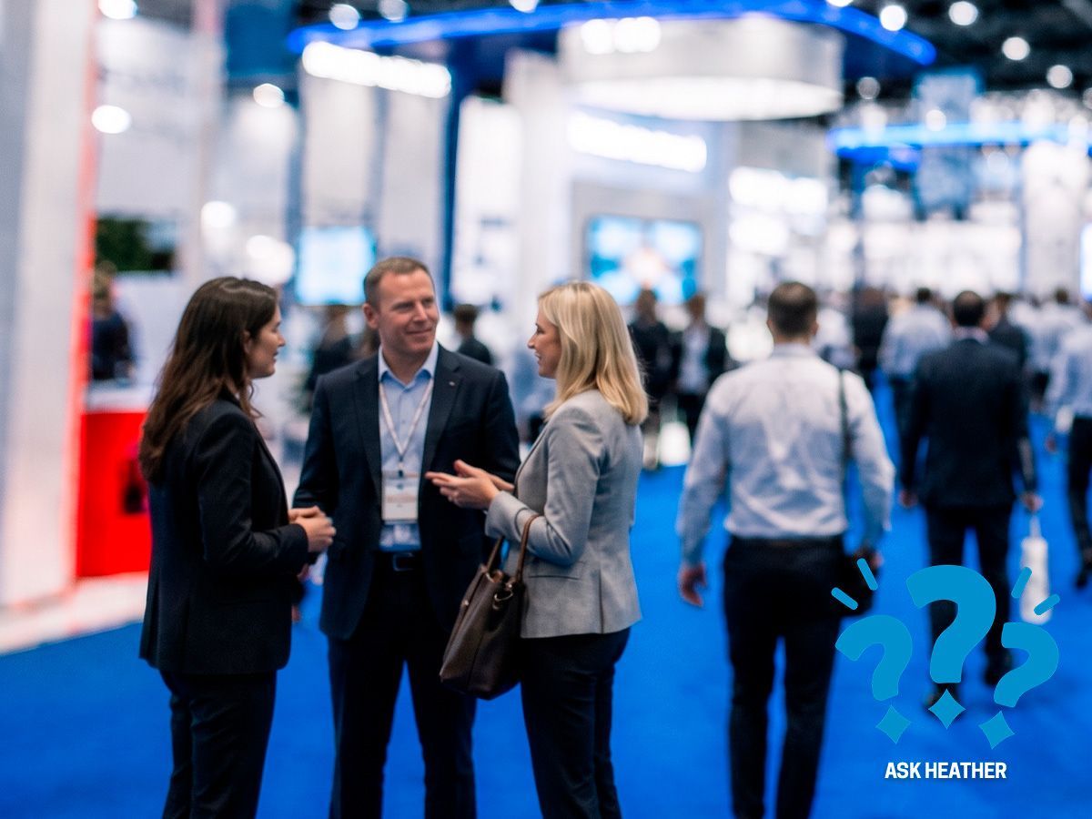Crowded trade show floor with people walking on a blue carpet under bright exhibition lights