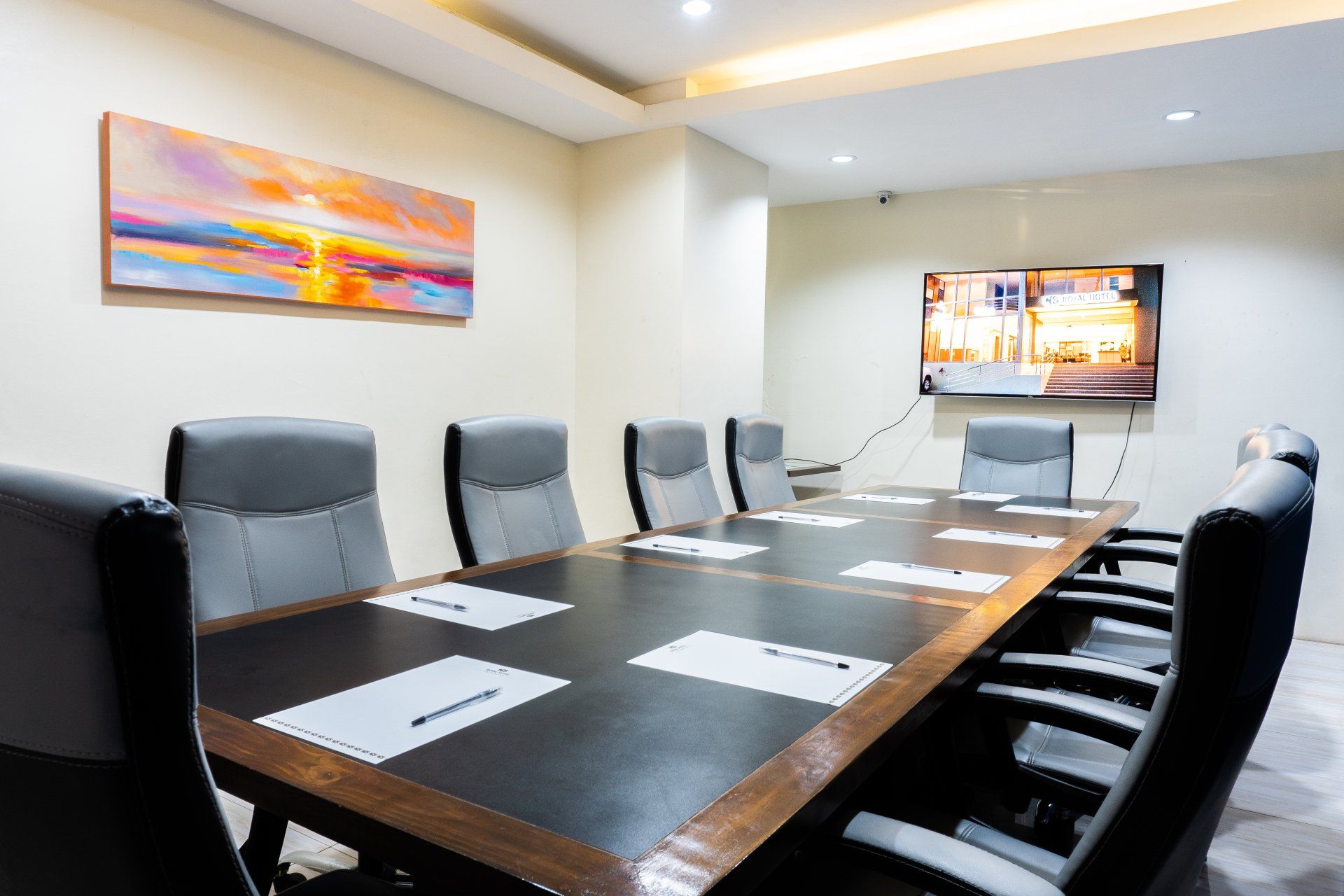 A conference room with a long table and chairs and a television on the wall.