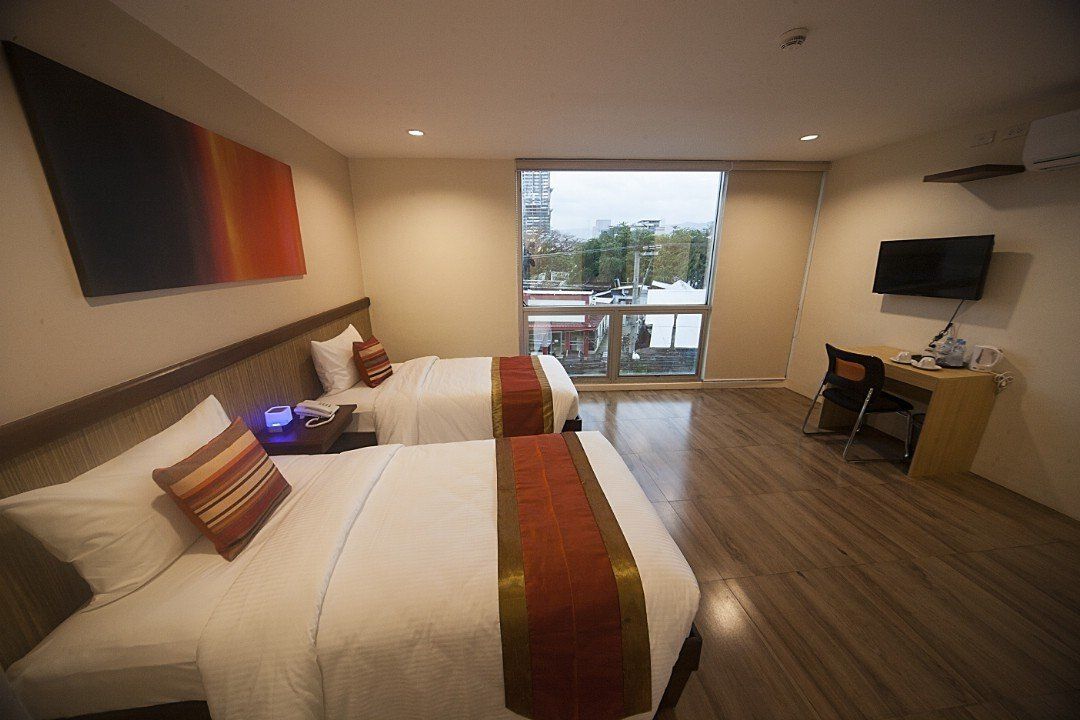 A hotel room with two beds , a desk and a television.