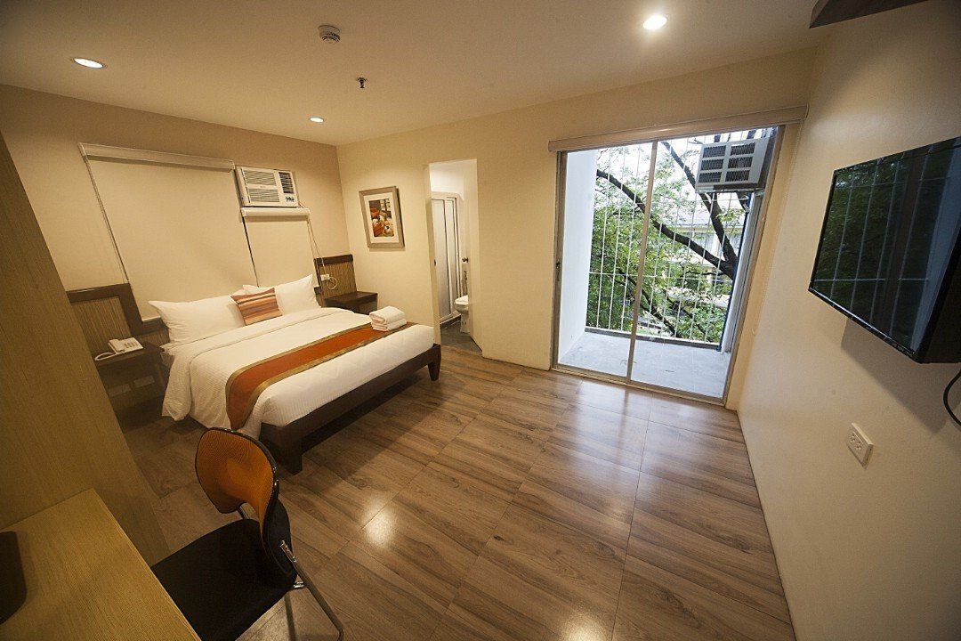 A hotel room with a large bed and a flat screen tv.