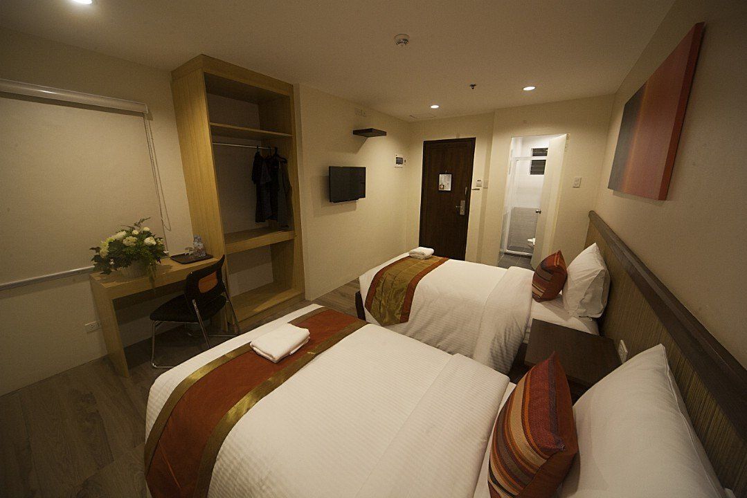 A hotel room with two beds , a desk and a television.