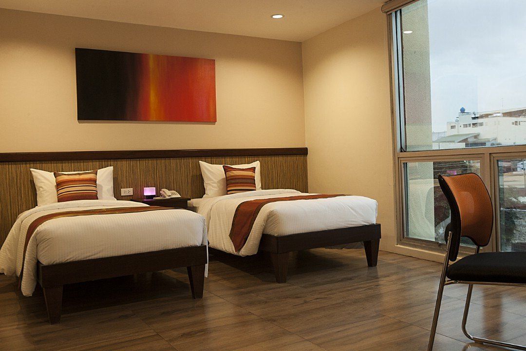 A hotel room with two beds , a chair and a large window.