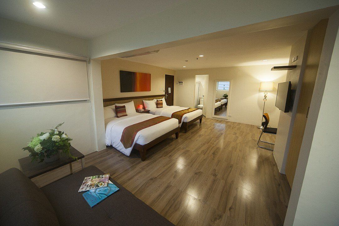 A hotel room with two beds , a couch , and a television.