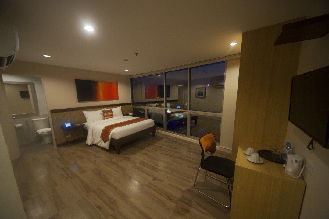 A hotel room with a bed , television , desk and chairs.