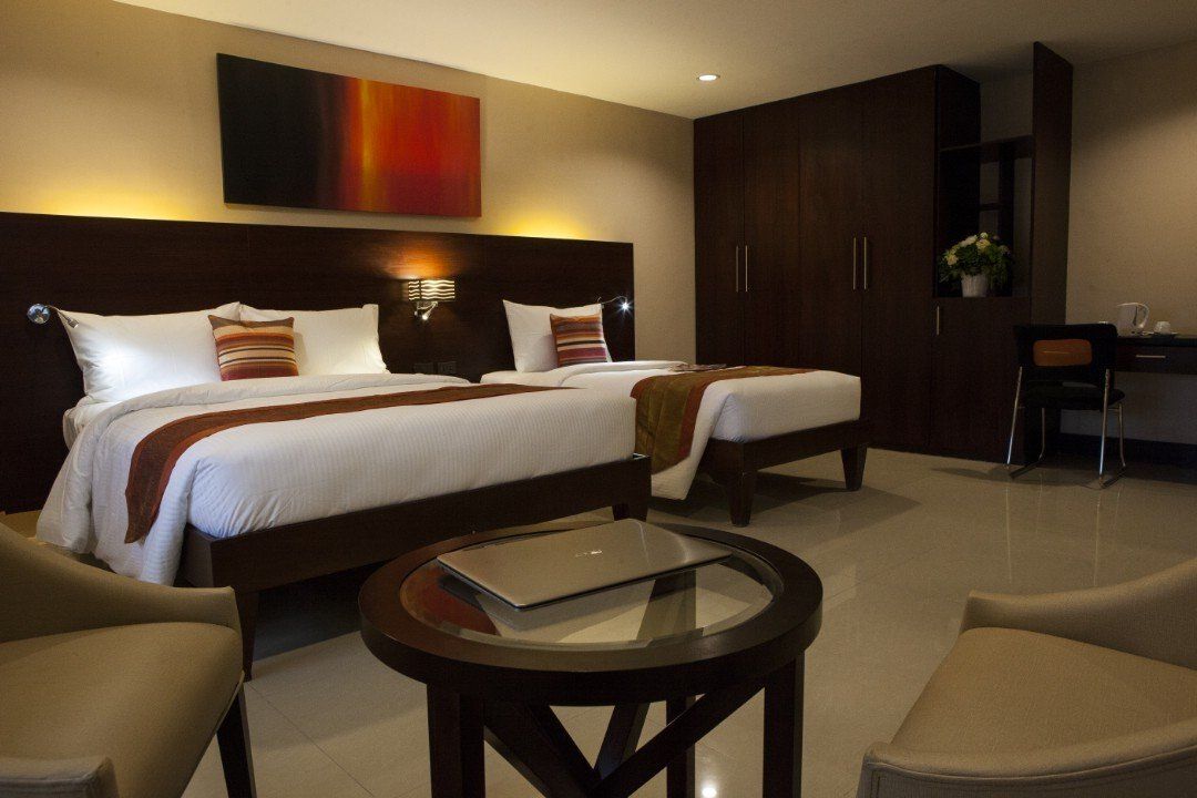 A hotel room with two beds and a table with a laptop on it.
