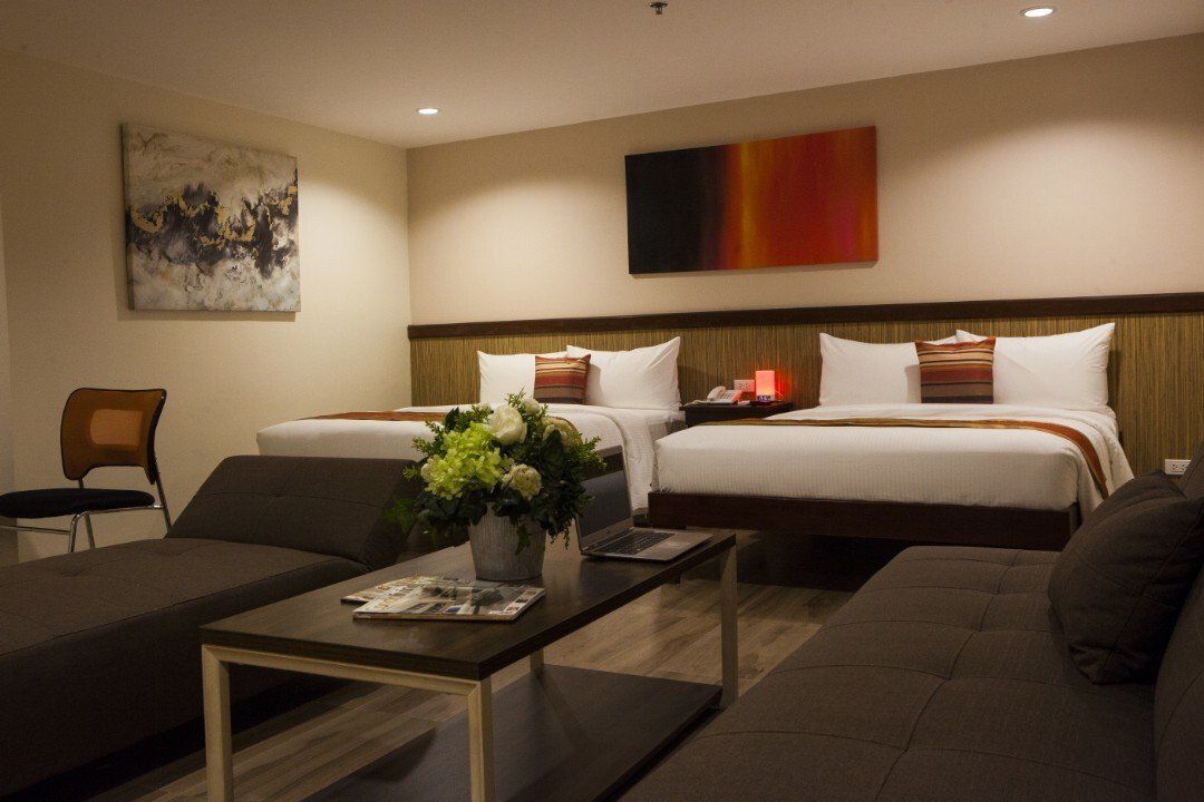 A hotel room with two beds , a couch , and a coffee table.