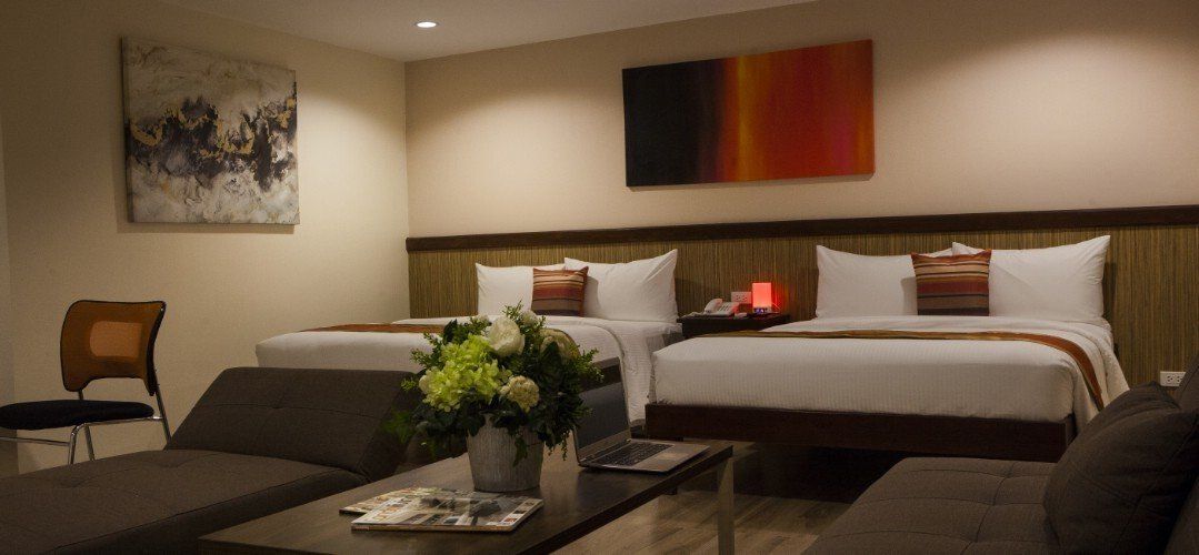 A hotel room with two beds , a couch , and a coffee table.
